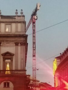 protest banner hung from crane outside La Scala opera house in Milan reading 